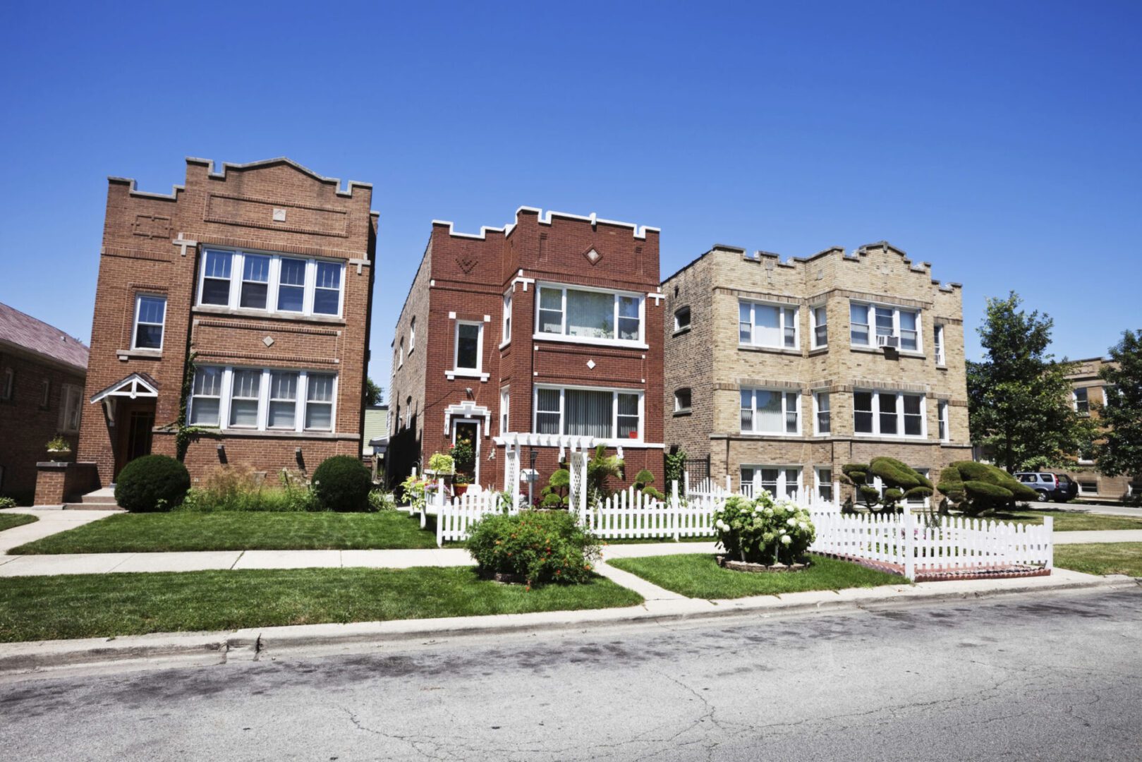 Three residential buildings with front lawns.